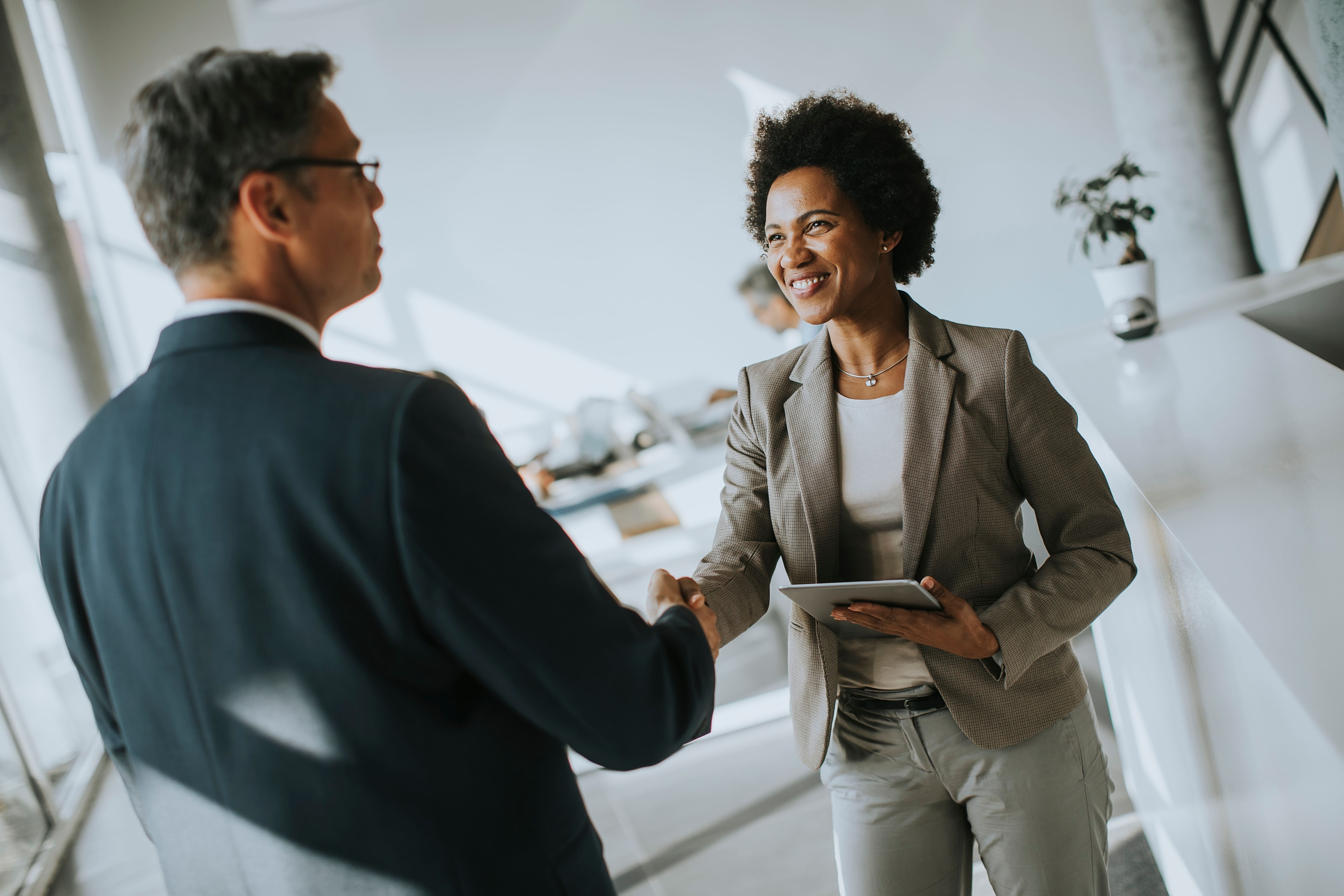 Smiling woman shaking hands with a man at the start of an interview.jpeg