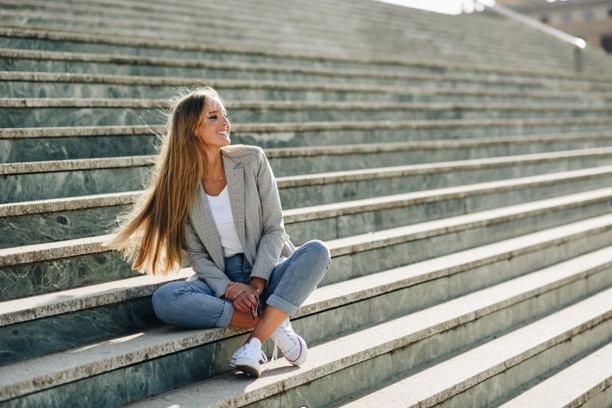 Woman wearing jeans with a tailored blazer and sneakers .png