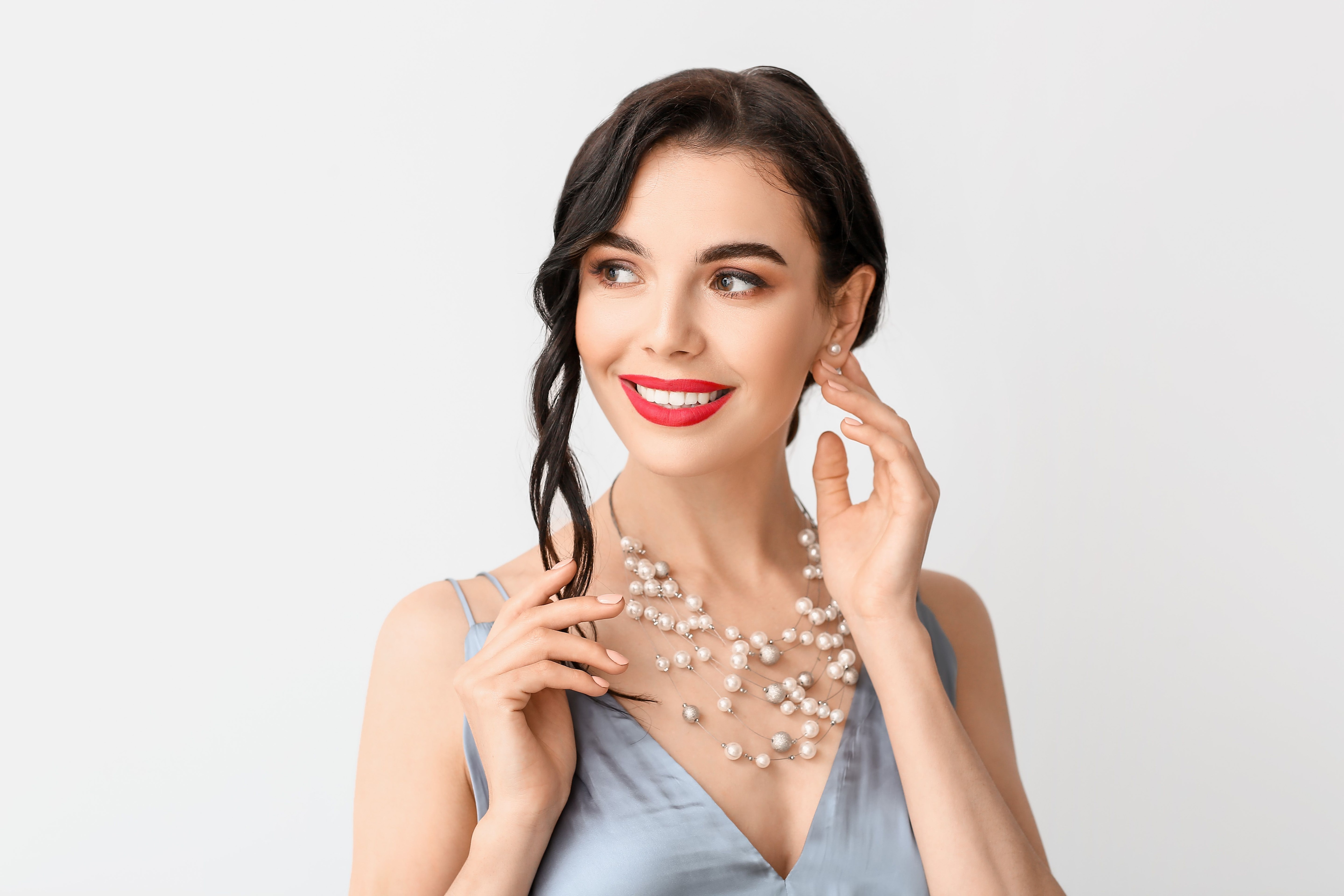 Smiling woman in a grey satin dress and multi-strand pearl necklace.jpeg