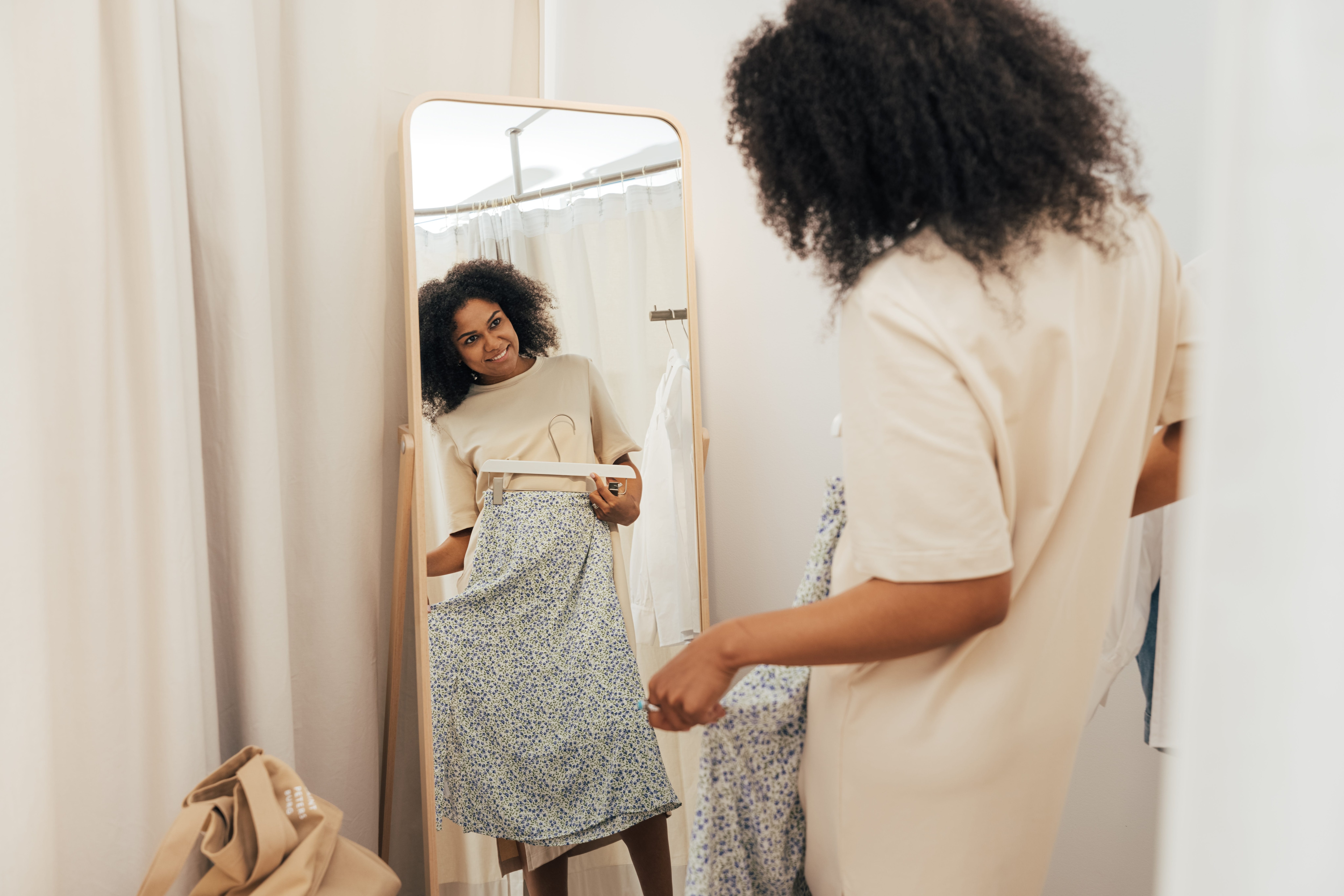 Woman holding up a skirt to herself in the mirror.jpeg